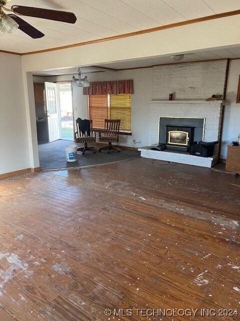 unfurnished living room with ceiling fan, a large fireplace, dark hardwood / wood-style floors, and crown molding