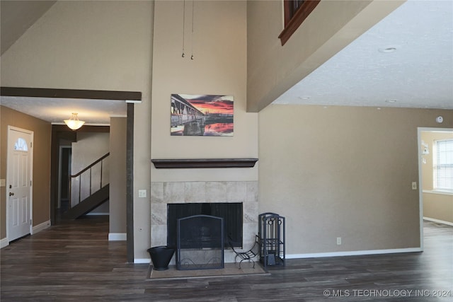 unfurnished living room with dark wood-type flooring and a tile fireplace