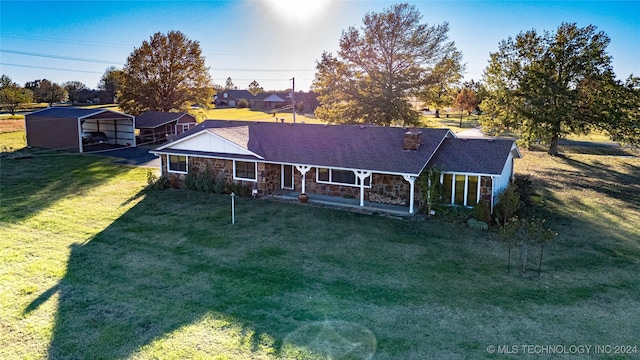 rear view of house with driveway, a yard, stone siding, and a detached carport