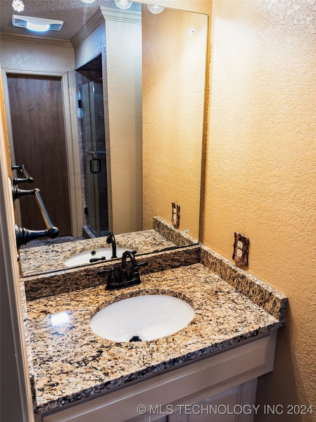 bathroom featuring a textured ceiling, a textured wall, and vanity