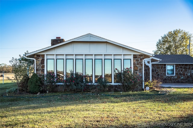 view of front of property featuring stone siding, a front lawn, and a chimney