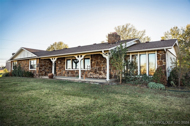 ranch-style house featuring stone siding, a chimney, a front lawn, and board and batten siding