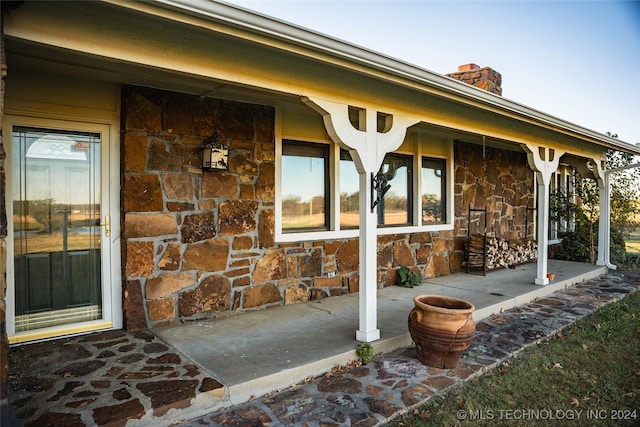 view of exterior entry featuring stone siding and a chimney