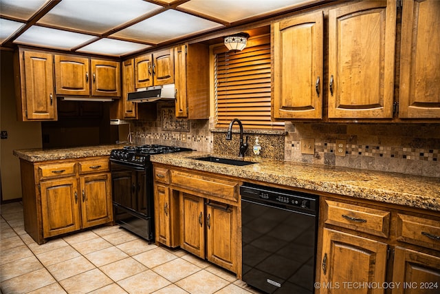 kitchen with brown cabinetry, a sink, under cabinet range hood, black appliances, and backsplash