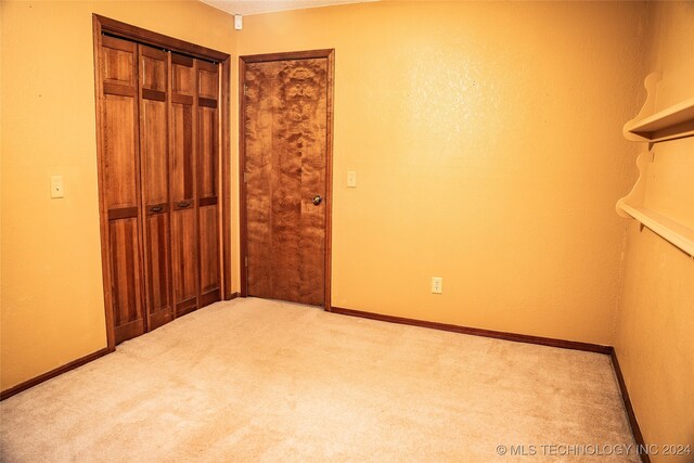 unfurnished bedroom featuring light colored carpet and a closet