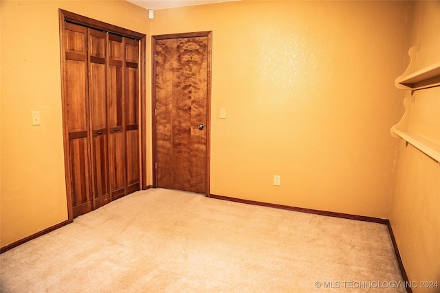 unfurnished bedroom featuring a closet, light colored carpet, and baseboards