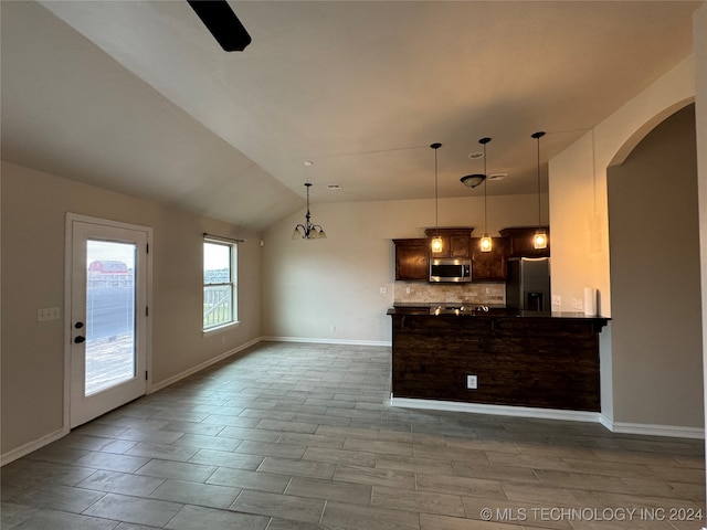 kitchen with appliances with stainless steel finishes, an inviting chandelier, backsplash, hanging light fixtures, and vaulted ceiling