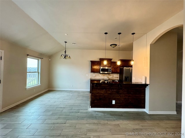 kitchen featuring vaulted ceiling, a notable chandelier, hanging light fixtures, backsplash, and appliances with stainless steel finishes