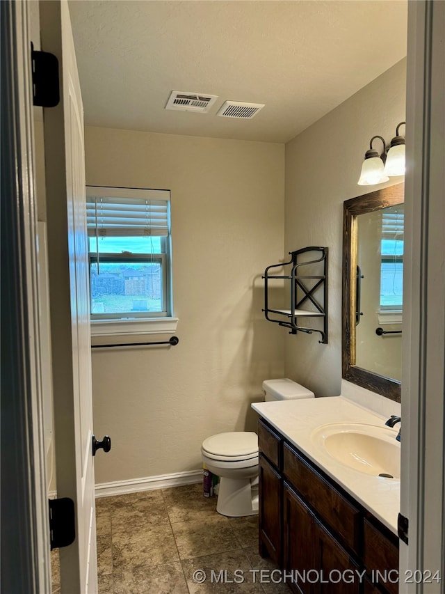 bathroom with vanity, a healthy amount of sunlight, and toilet