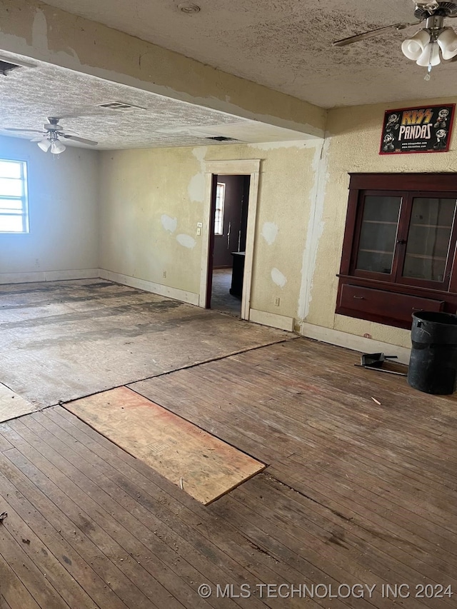 unfurnished room with ceiling fan, wood-type flooring, and a textured ceiling