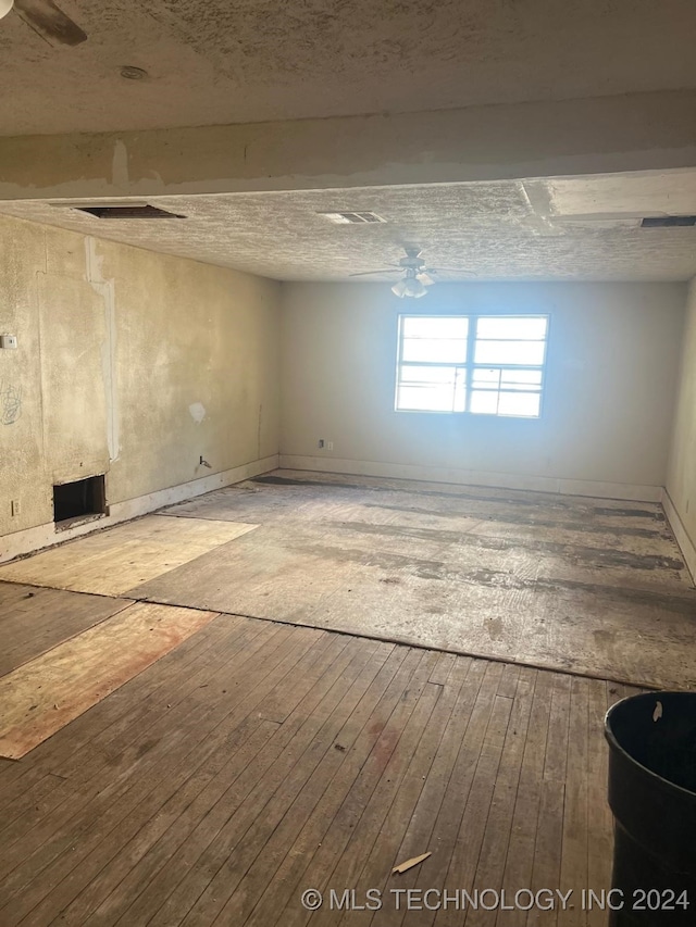 basement with hardwood / wood-style flooring, a textured ceiling, and ceiling fan