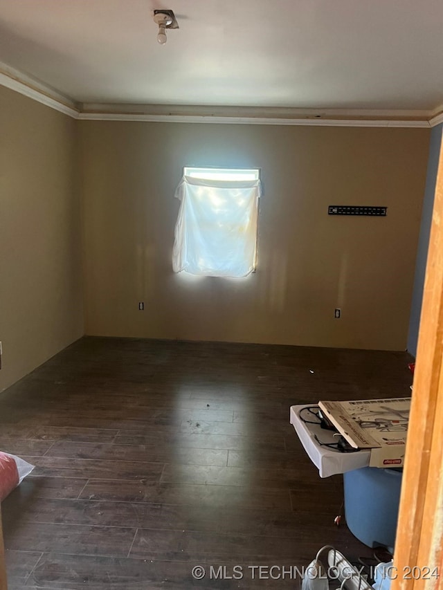 spare room with dark wood-type flooring and crown molding