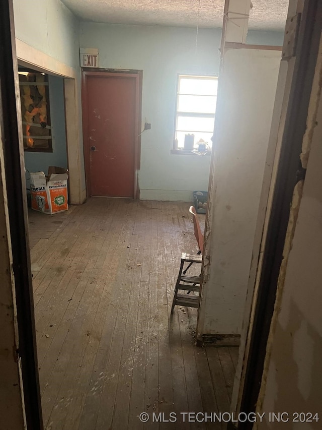 hall featuring a textured ceiling and hardwood / wood-style flooring