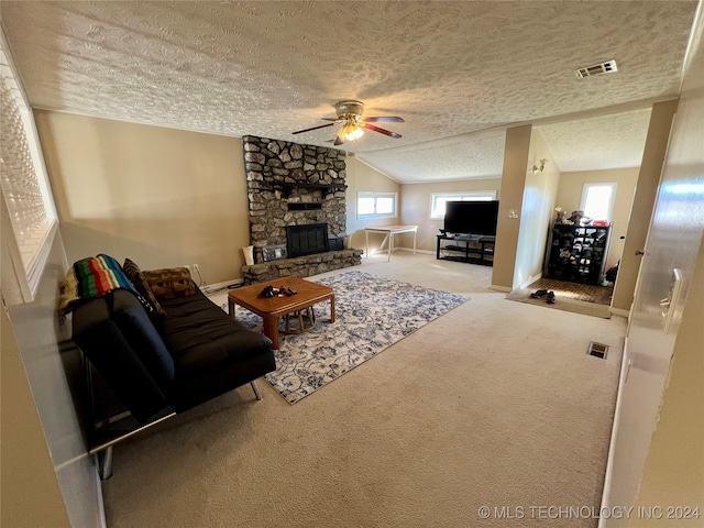 carpeted living room featuring ceiling fan, a textured ceiling, a stone fireplace, and lofted ceiling