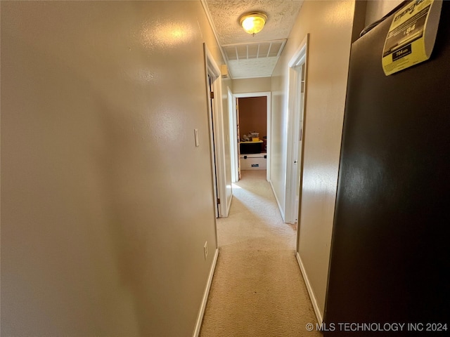 hallway featuring a textured ceiling and light carpet