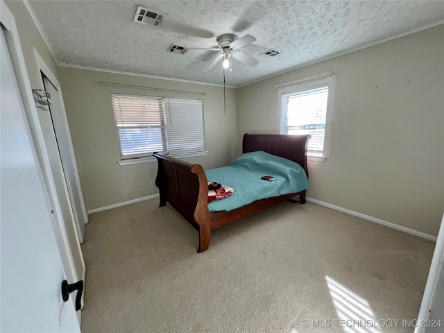 bedroom with ornamental molding, a textured ceiling, light colored carpet, and ceiling fan