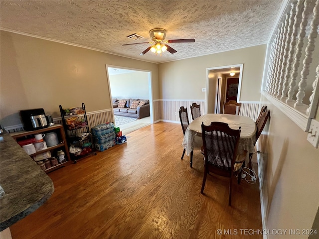 dining space featuring hardwood / wood-style flooring, ceiling fan, a textured ceiling, and ornamental molding