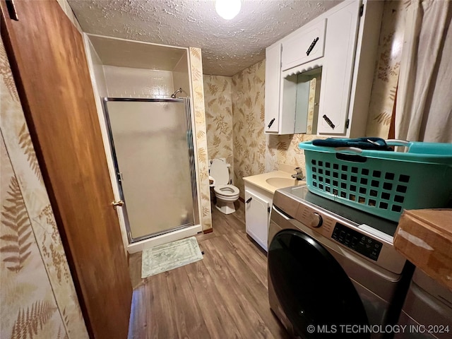 bathroom featuring wood-type flooring, washer / dryer, walk in shower, a textured ceiling, and toilet