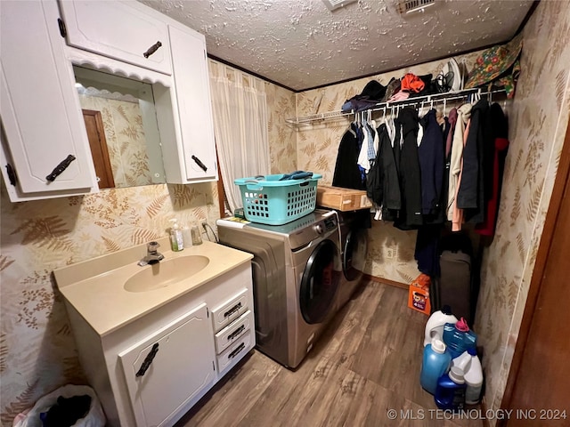 laundry area featuring cabinets, sink, a textured ceiling, wood-type flooring, and washing machine and dryer