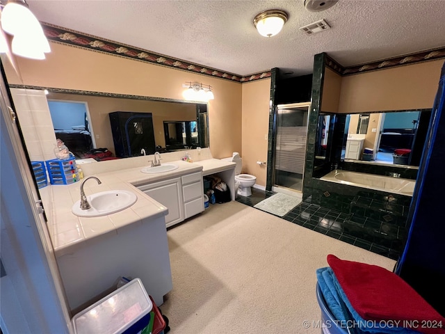 full bathroom featuring toilet, vanity, a textured ceiling, and separate shower and tub