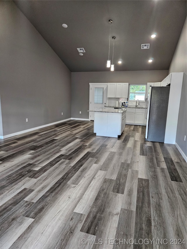 kitchen featuring pendant lighting, hardwood / wood-style flooring, white cabinets, a center island, and stainless steel refrigerator