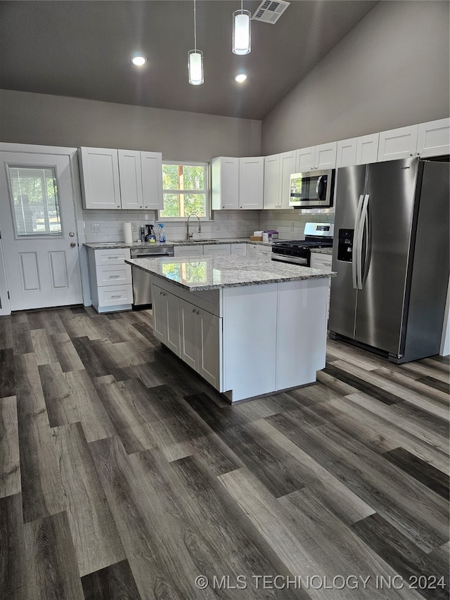 kitchen featuring stainless steel appliances, sink, decorative light fixtures, white cabinets, and a kitchen island