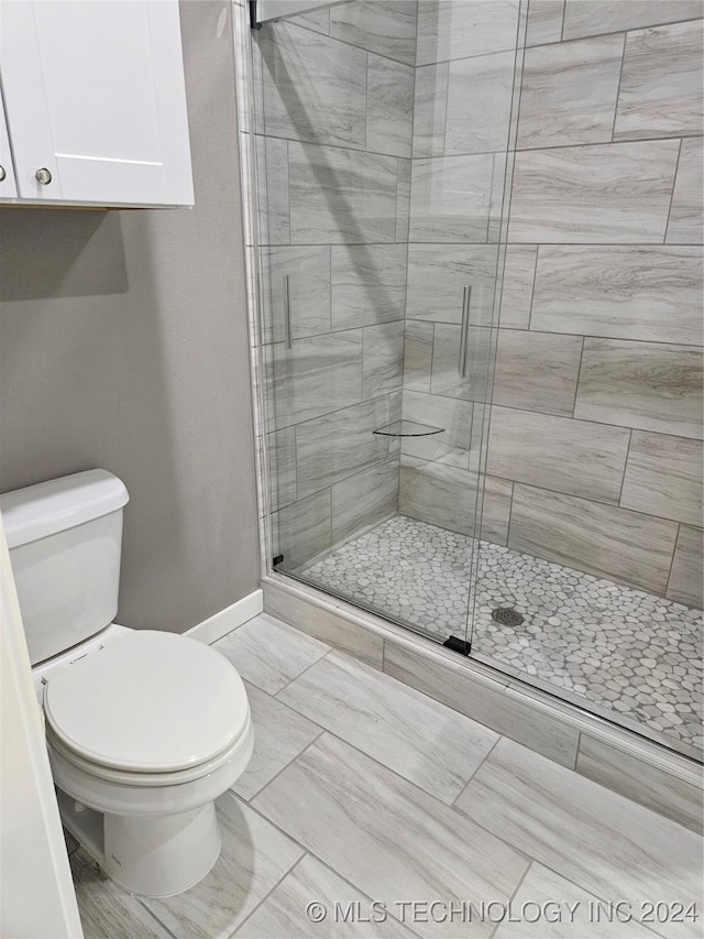 bathroom with toilet and a shower with shower door