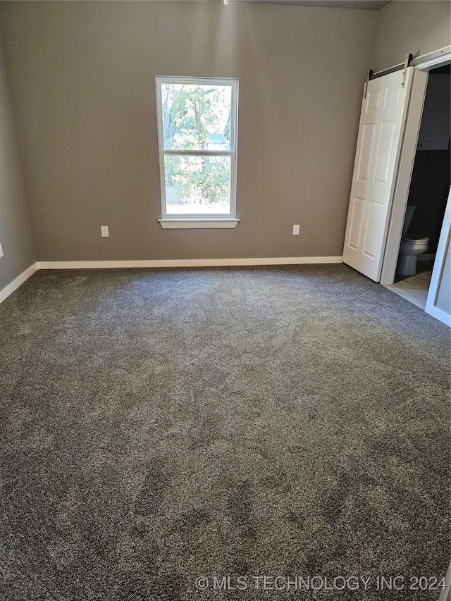 carpeted empty room with a barn door