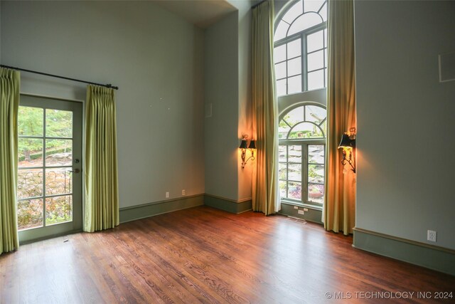 8403 S Allegheny Ave, Tulsa, OK 74137 - empty room with plenty of natural light, a high ceiling, wood finished floors, and baseboards