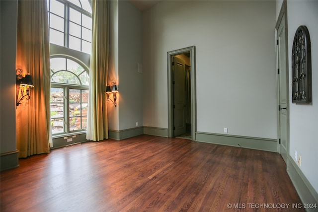 empty room featuring dark hardwood / wood-style floors and a towering ceiling