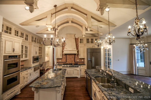 kitchen featuring built in appliances, a large island, sink, and decorative light fixtures