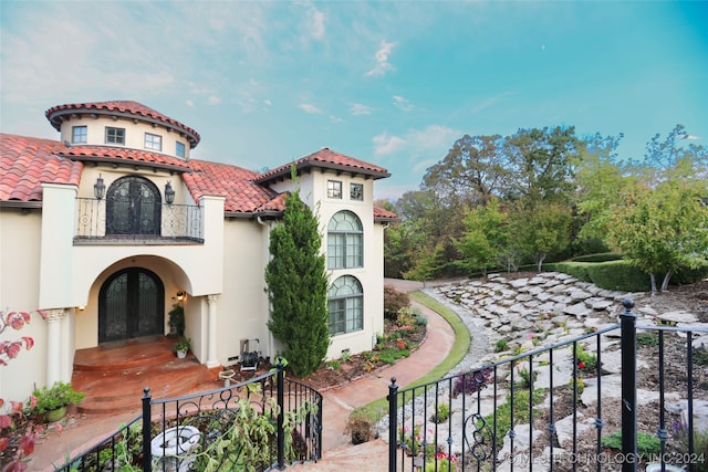 mediterranean / spanish home featuring a balcony and french doors