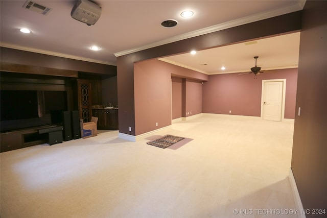 basement with crown molding, sink, ceiling fan, and light colored carpet