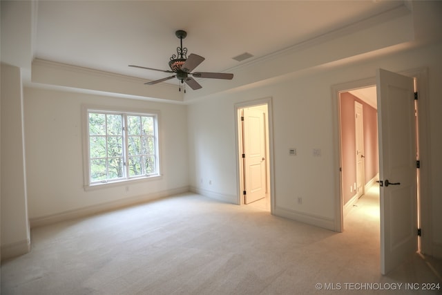 unfurnished bedroom with light carpet, a raised ceiling, ceiling fan, and crown molding