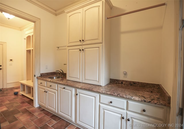 kitchen featuring white cabinets, dark stone counters, crown molding, and sink