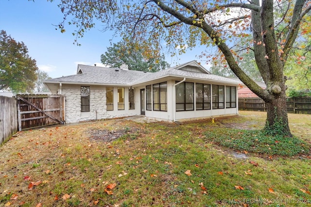 rear view of house featuring a lawn and a sunroom