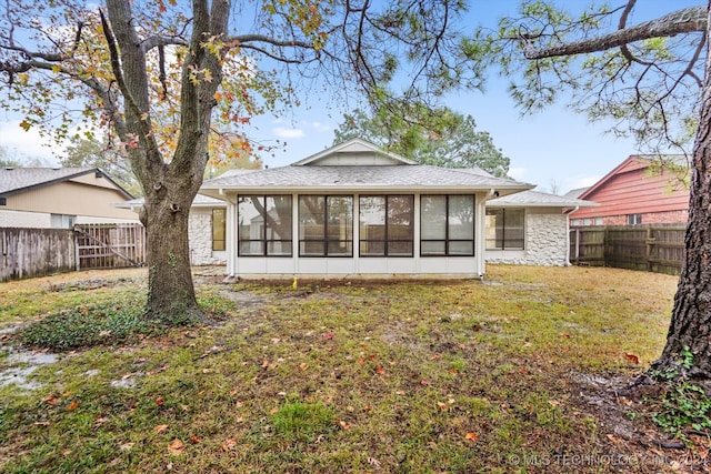 back of property featuring a lawn and a sunroom