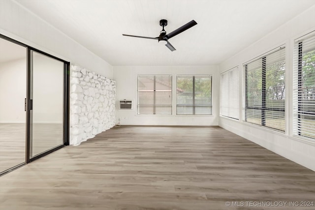 unfurnished sunroom featuring a wall mounted air conditioner and ceiling fan