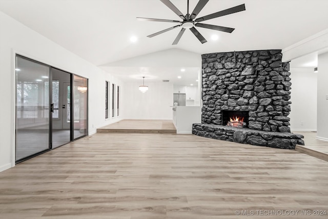 unfurnished living room featuring ceiling fan, a stone fireplace, light wood-type flooring, and vaulted ceiling