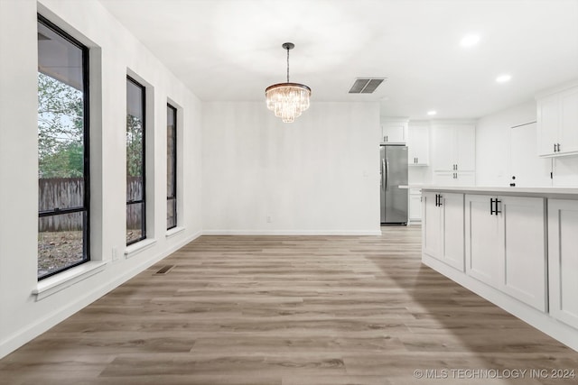 unfurnished dining area featuring light wood-type flooring and a notable chandelier