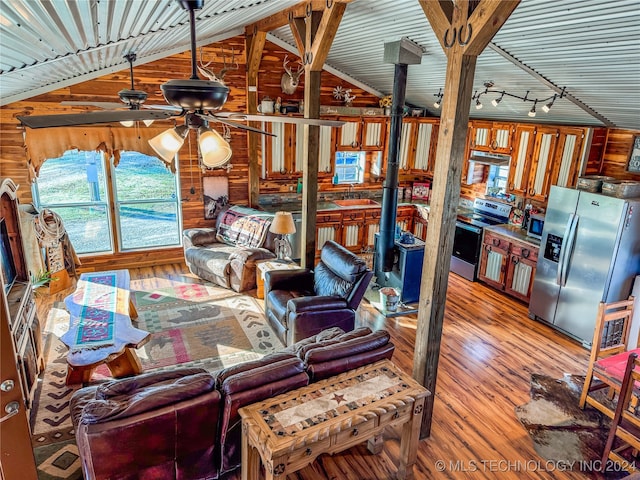 living room with lofted ceiling, wood-type flooring, wood walls, sink, and ceiling fan