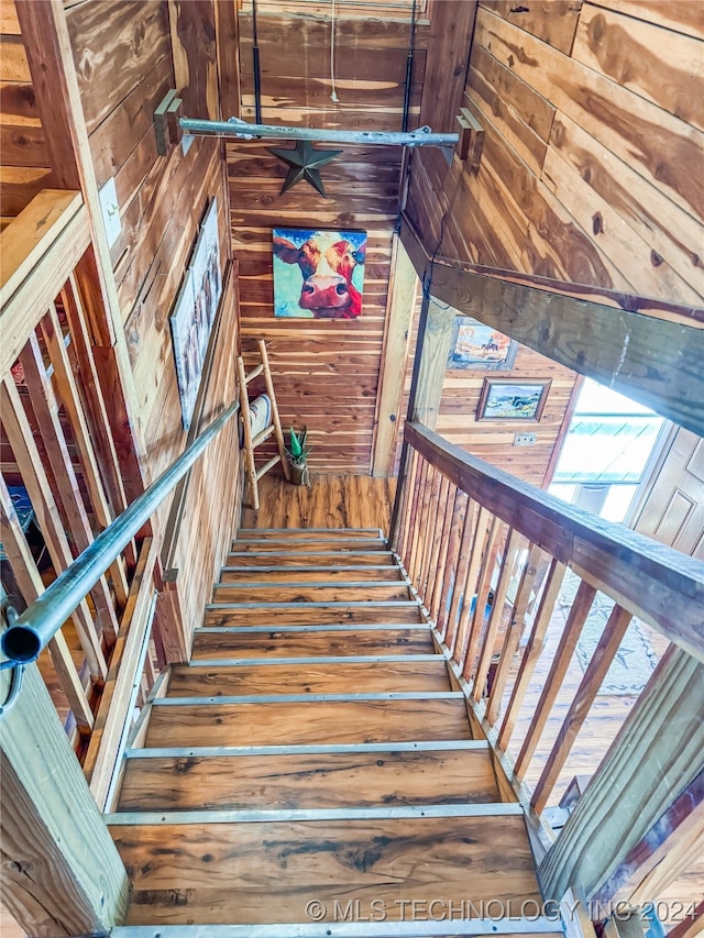 stairway with hardwood / wood-style floors and wooden walls