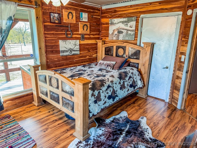 bedroom featuring wood walls and hardwood / wood-style flooring