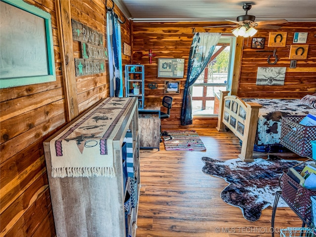 bedroom with wood walls, hardwood / wood-style floors, and ceiling fan