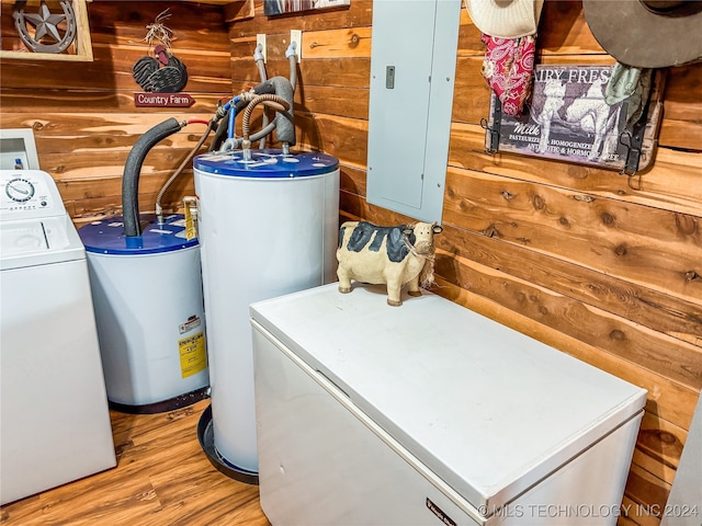 laundry area featuring electric panel, light wood-type flooring, wooden walls, and gas water heater