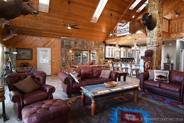 living room featuring wood walls, ceiling fan with notable chandelier, a skylight, high vaulted ceiling, and wood ceiling