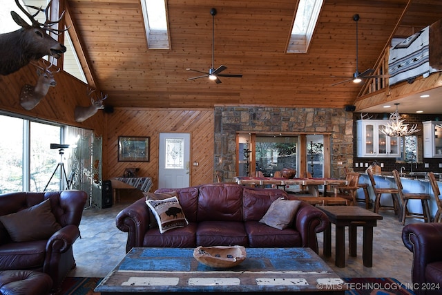 living room featuring ceiling fan with notable chandelier, a skylight, high vaulted ceiling, wood ceiling, and wooden walls