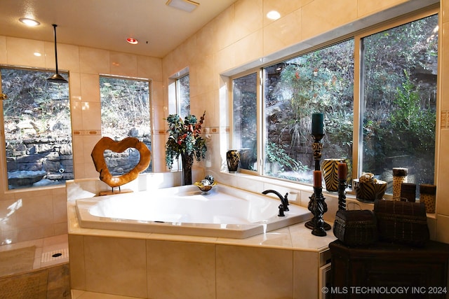 bathroom featuring tile walls, tiled bath, and plenty of natural light