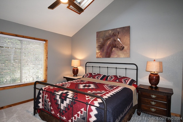 carpeted bedroom featuring vaulted ceiling with skylight and ceiling fan