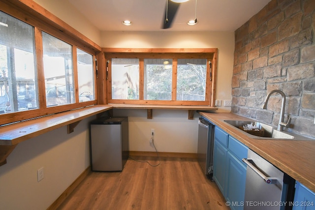 kitchen with light hardwood / wood-style floors, sink, stainless steel dishwasher, blue cabinets, and butcher block countertops